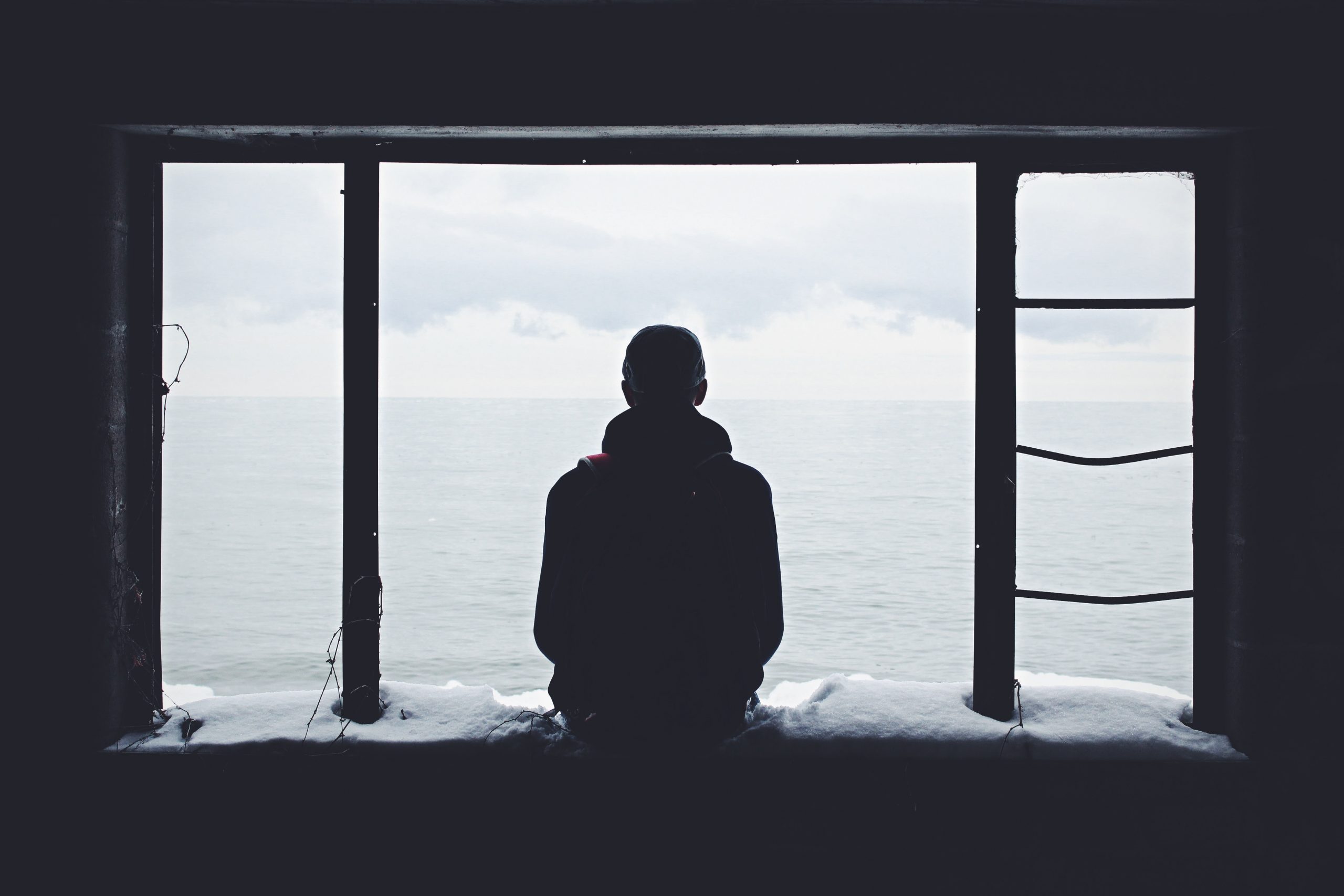 man sitting on ledge looking out at the ocean